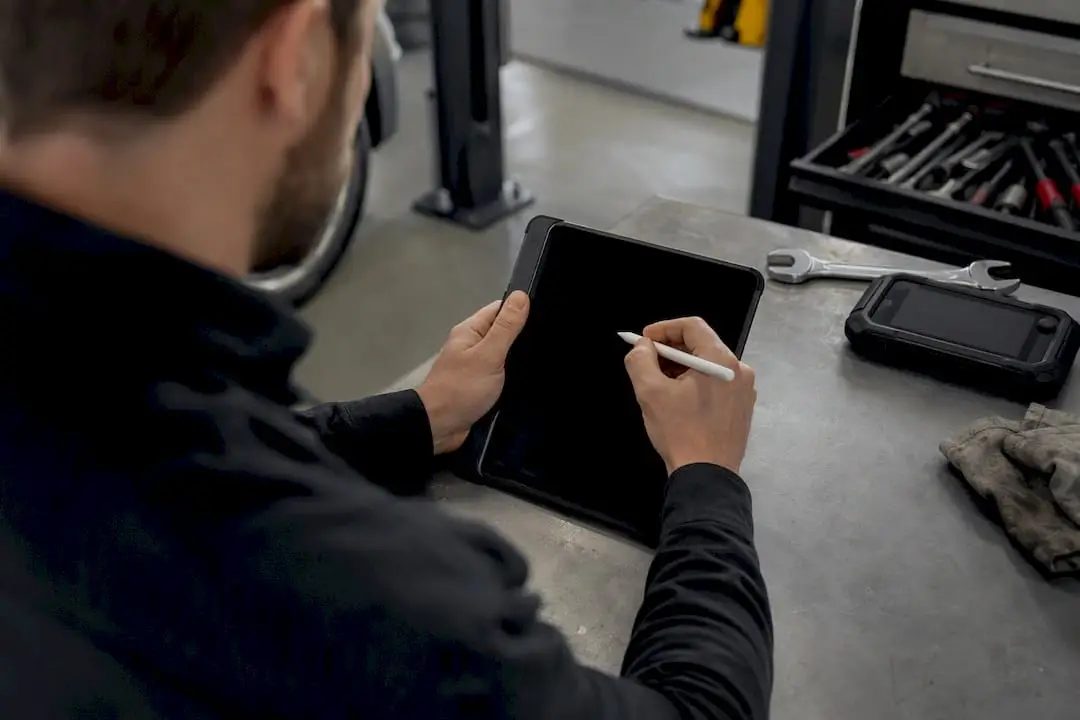 Technician hands drafting maintenance plan on tablet