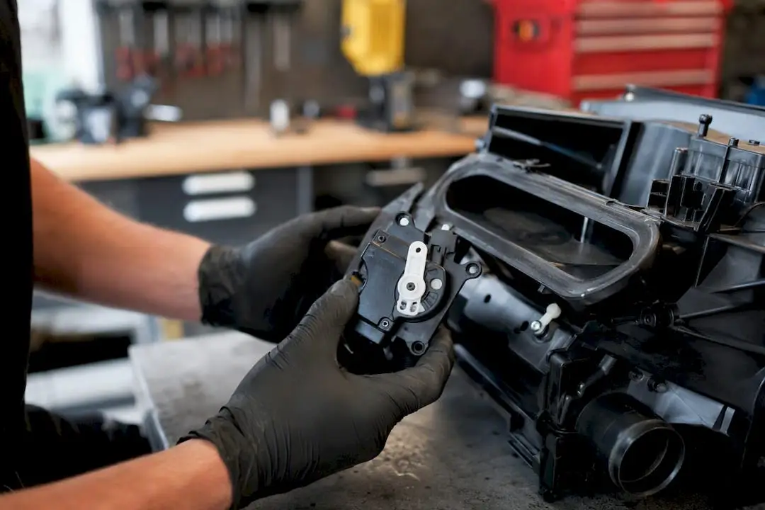Hand holding HVAC blend door actuator near duct